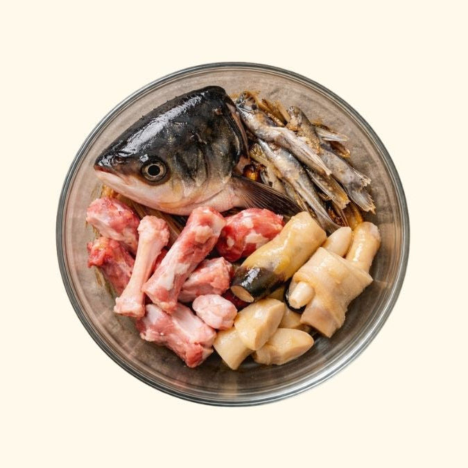 Raw fish and meat in a metal bowl on a white background